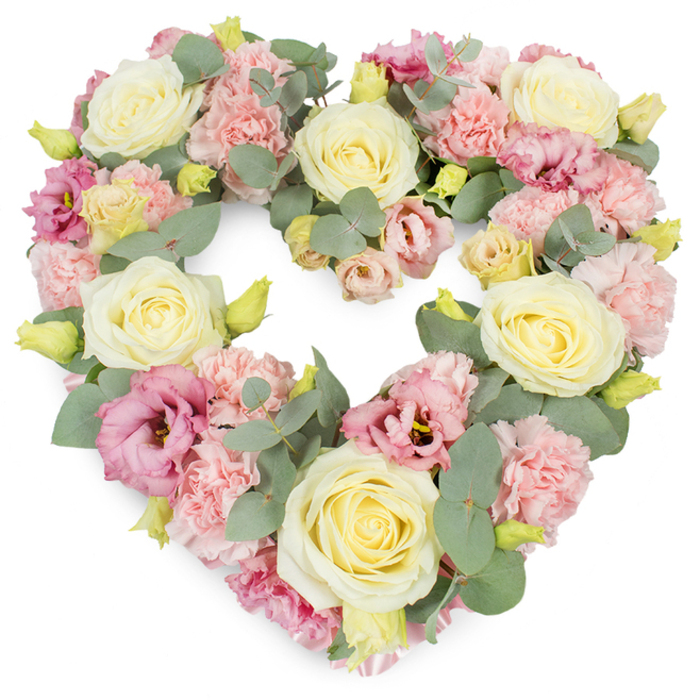 A full and luxurious heart-shaped floral tribute is captured against a bright white background, its carefully selected pastel flowers and greenery creating a serene and comforting impression. The heart itself is clearly defined and generously filled, as though every blossom has been nestled close to its neighbour to convey closeness and unity. Dominating the design are large cream and soft yellow roses, their velvety petals wound tightly at the centre and opening gradually outward, giving each bloom an elegant, timeless look associated with deep affection and respect. Between these roses, clusters of light pink carnations provide a soft, textured contrast, their frilled petals introducing a sense of warmth and tenderness. Throughout the wreath, deeper rose-pink and mauve lisianthus flowers punctuate the paler tones, their looser, bell-shaped petals adding gentle movement and depth. Silvery-green eucalyptus leaves weave through the arrangement, following the curve of the heart and adding a cool, muted green that balances the sweetness of the flowers, a little like the calming expanses of green around Basildon's Langdon Hills. Small, yellow-green buds appear here and there, subtle reminders of new life and the continuity of love. The overall mood is reflective and peaceful, making this heart wreath ideal as a funeral, cremation, or memorial tribute in Basildon, whether delivered to a local chapel, church, or directly to a family home. Crafted with the precision of an experienced florist at Flower Delivery Basildon, the arrangement feels both personal and dignified, a fitting floral expression for saying farewell, offering condolences, and honouring treasured memories within the local community.