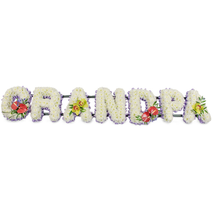 A striking word tribute in flowers spells GRANDPA in big, confident block letters, displayed in a straight line as if resting on trestles at the front of a funeral service in Basildon. Every letter is filled completely with masses of white chrysanthemums, arranged so tightly that the blooms form a continuous, soft-textured surface, their delicate petals symbolising purity, peace, and the tenderness of family memories. At the lower edge of each letter, a fine border of pale lavender ribbon peeks out, forming a gentle halo of lilac that traces the outline of the word and adds a quiet touch of colour. The letters are mounted along dark green bars that lend support while blending into the background so that what the eye really reads is simply a name for a much-loved role in the family. Carefully placed accent sprays bring life and personality to the design. On the opening G and the central D, clusters of deep red anthuriums stand proudly, their glossy, heart-shaped spathes and vivid yellow spadices glowing against the white chrysanthemum bed. These are framed with rich green foliage and a few sprigs of purple flowers, echoing emotions of deep love and gratitude. The first and final A feature sprays of lime-tinted orchids, their graceful petals and elegant form adding a contemporary, almost ethereal beauty. The palette of pure white, strong red, lime green, and soft lavender feels both composed and comforting. It is the type of bespoke funeral flower tribute Flower Delivery Basildon might create for same-day delivery to a local chapel or cemetery, offering a dignified, heartfelt farewell to a grandfather who meant the world to his family.